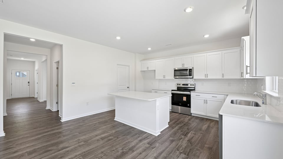 kitchen with quartz counters, kitchen island, pantry, stainless steel appliances