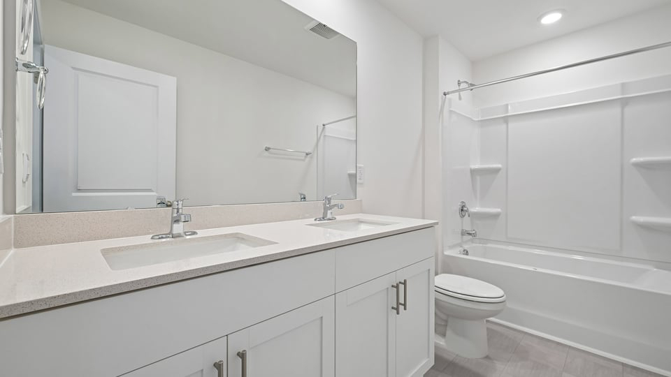 secondary bathroom with shower tub combo and dual vanity sink