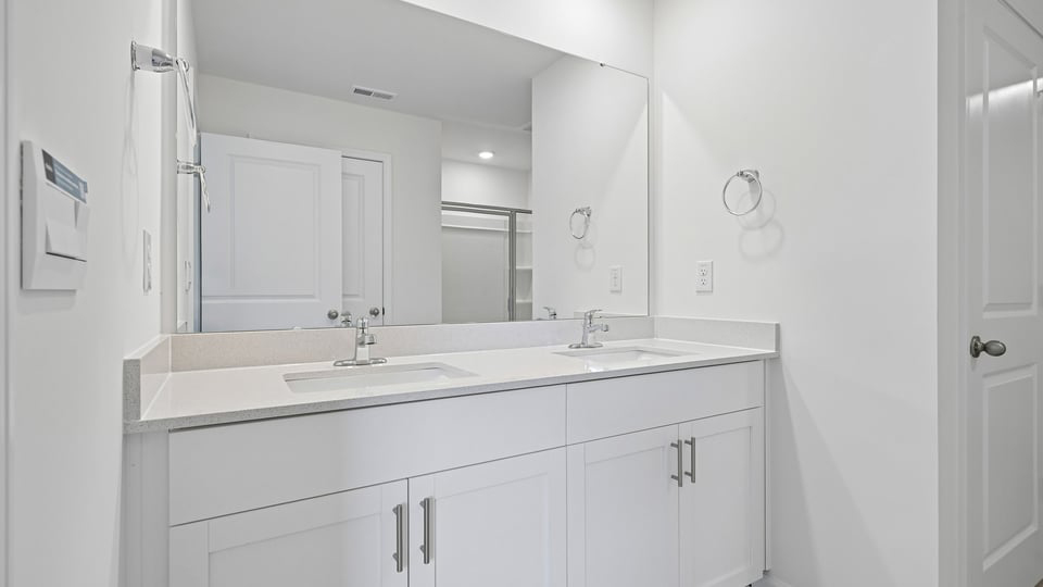primary bathroom with walk in shower and dual vanity sinks