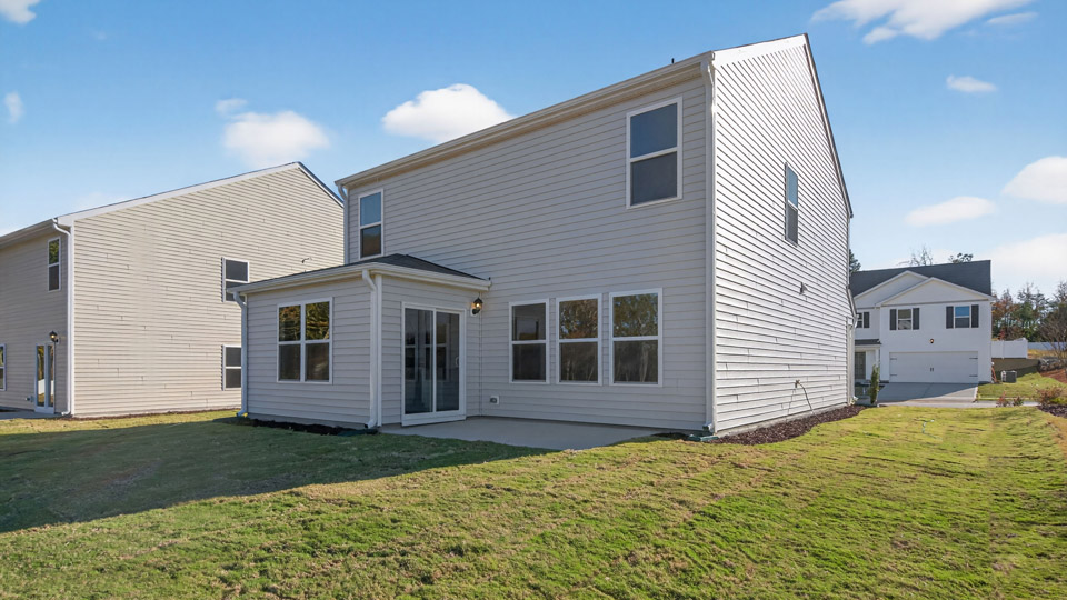 Two story home with white siding and back patio.