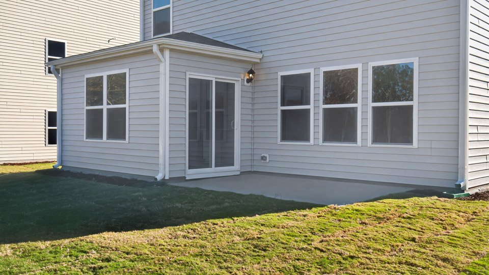 Two story home with white el siding and back patio.