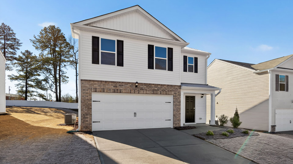 Two story home with white colored siding and front porch and a two car garage