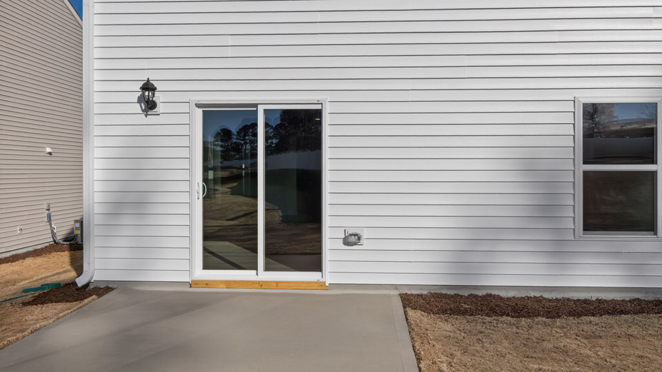 Two story home with white colored siding and back patio