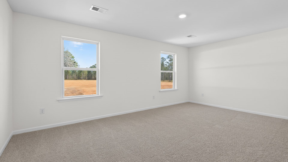 Primary bedroom with carpet floors and windows with access to the primary bathroom