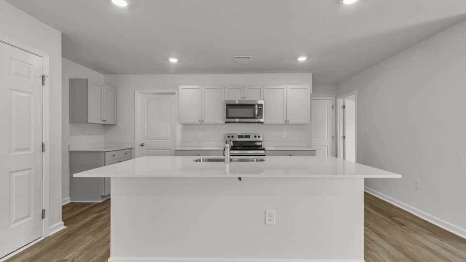 kitchen with quartz counters, kitchen island, pantry, stainless steel appliances