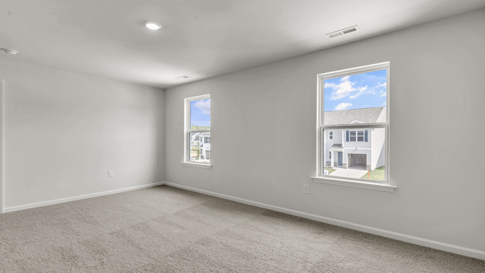 primary bedroom with two windows and carpeting, attached bath