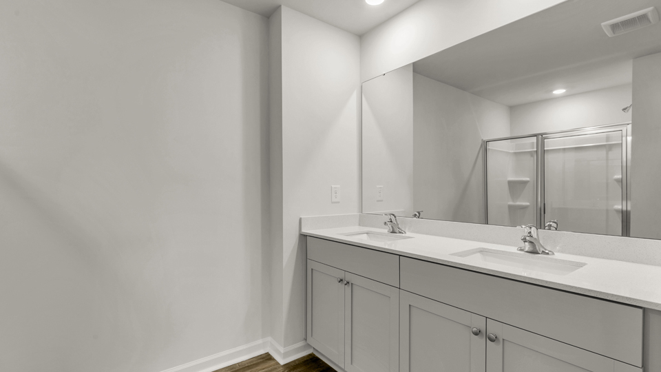 primary bathroom with walk in shower and dual vanity sinks
