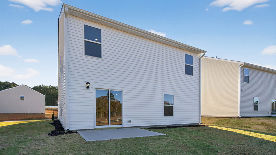 Two story home with white siding and back patio.