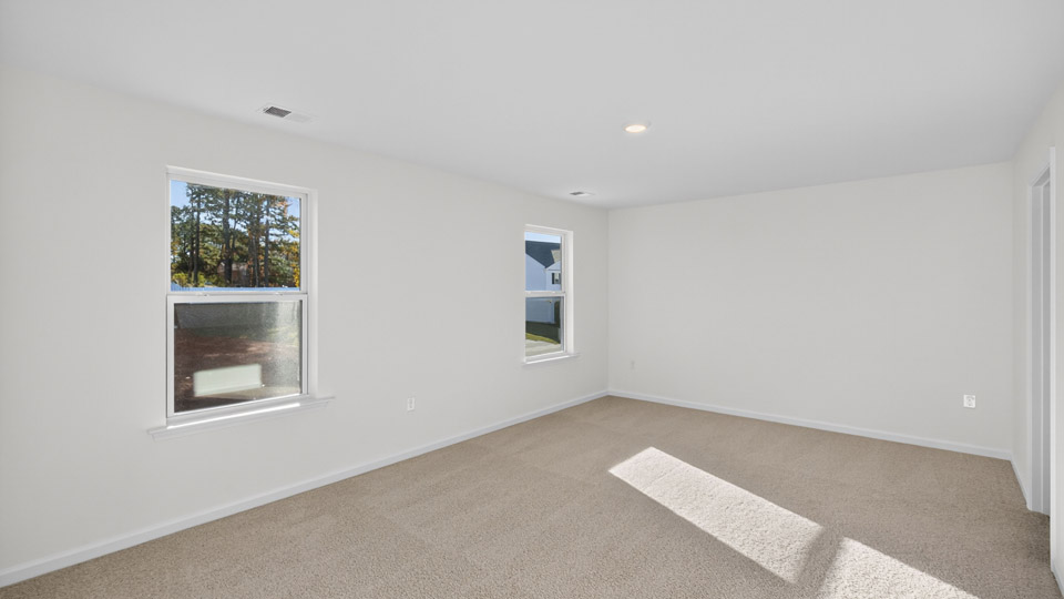 Primary bedroom with carpet and 2 windows