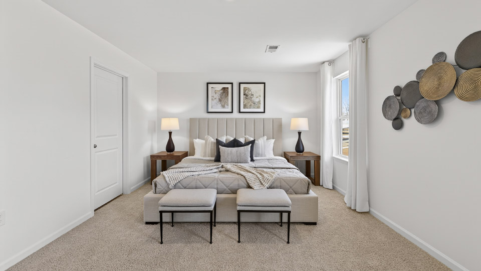 Primary bedroom with carpet floors and windows with access to the primary bathroom