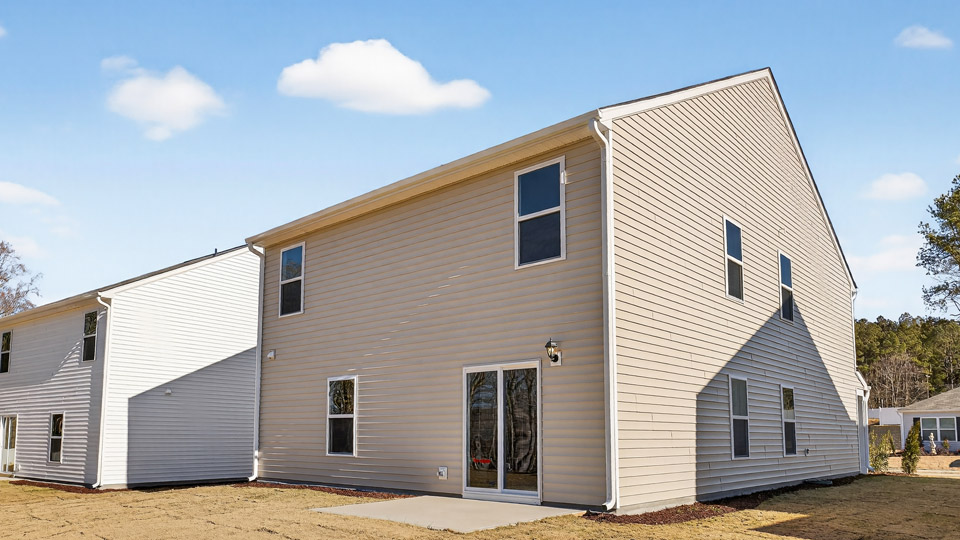 Two story home with yellow siding and patio