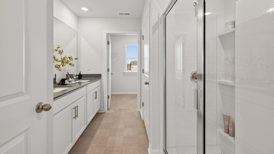 bathroom with white cabinets quartz countertops and walk-in shower with glass doors