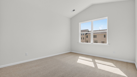 primary bedroom with vaulted ceiling and carpet flooring