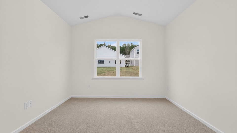 Primary bedroom with carpet floors and windows with access to the primary bathroom