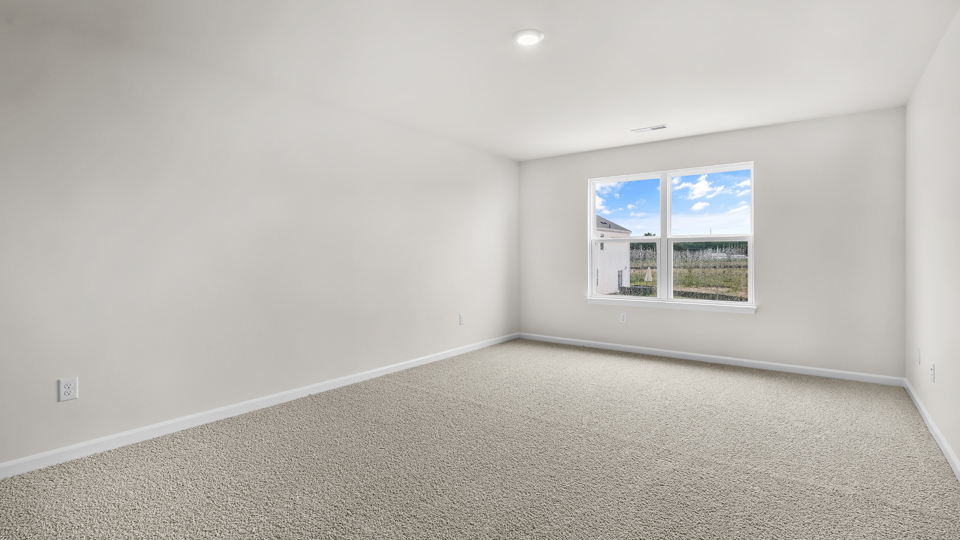 primary bedroom with two windows and carpeting, attached bath
