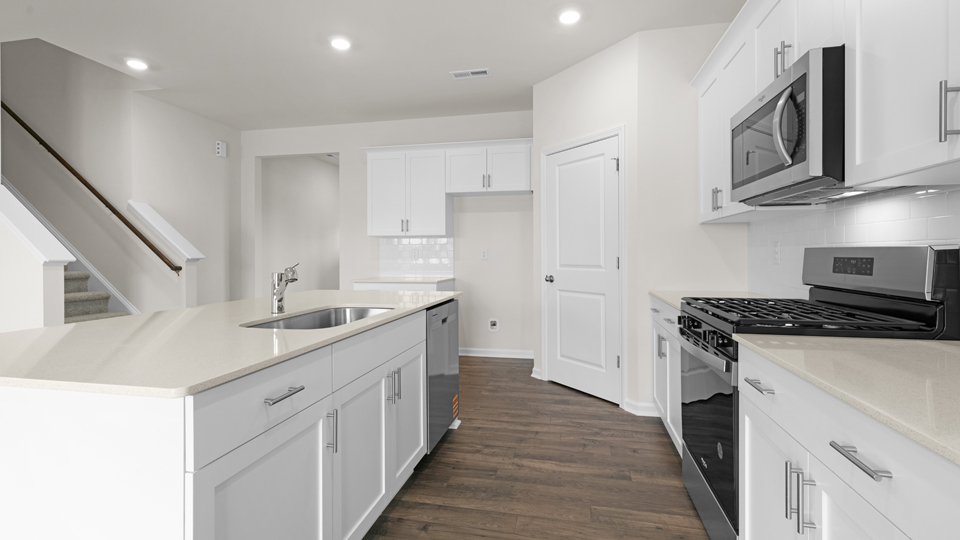 kitchen with quartz counters, kitchen island, pantry, stainless steel appliances