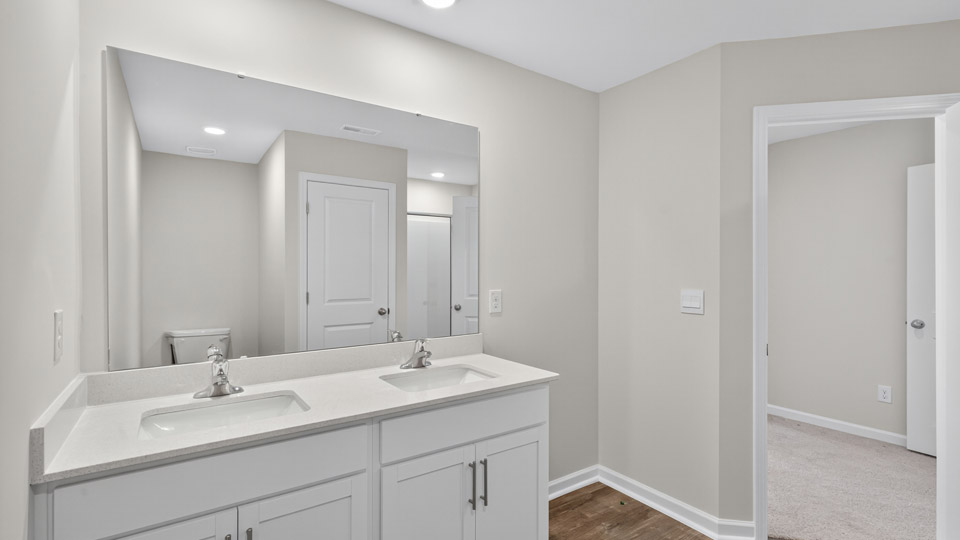 bathroom with dual vanity white cabinets and quartz countertops and walk-in closet
