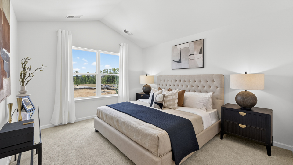 primary bedroom with two windows and carpeting, attached bath