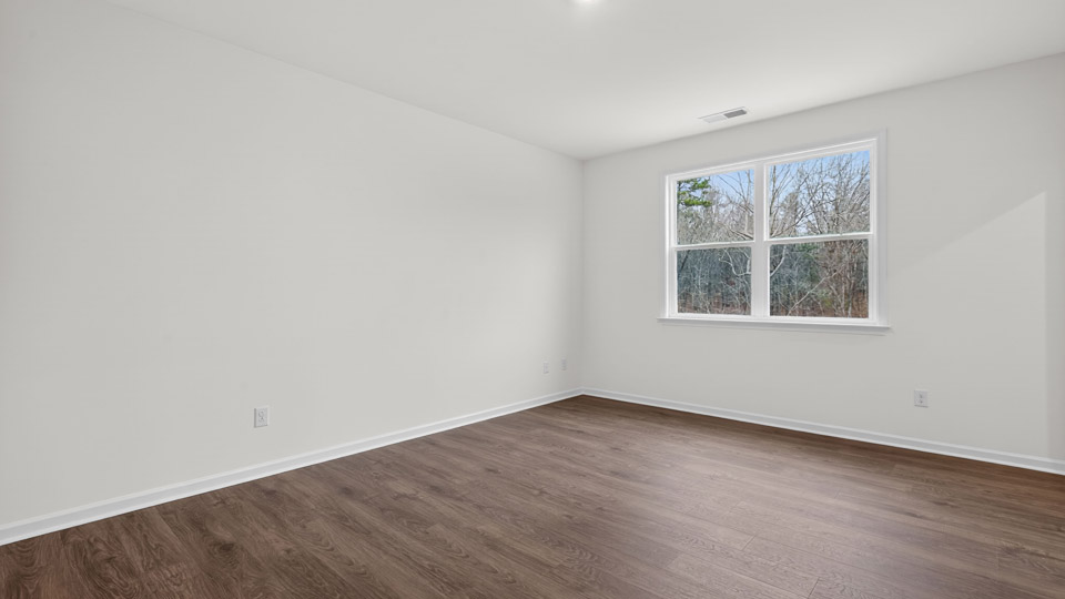 Primary bedroom with hardwood floors and windows with access to the primary bathroom