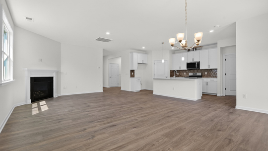 kitchen and open concept living room with fireplace and revwood flooring