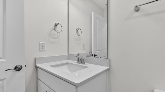 bathroom with white cabinets and quartz countertops