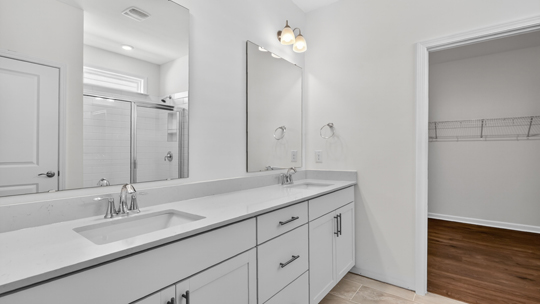 bathroom with dual vanity quartz countertops and walkin closet