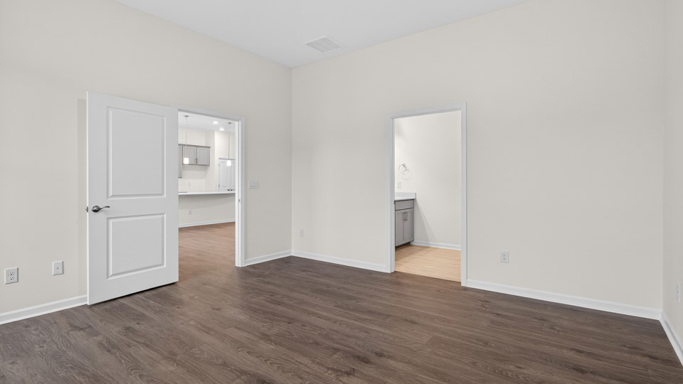 Primary bedroom with hardwood floors and windows with access to the primary bathroom