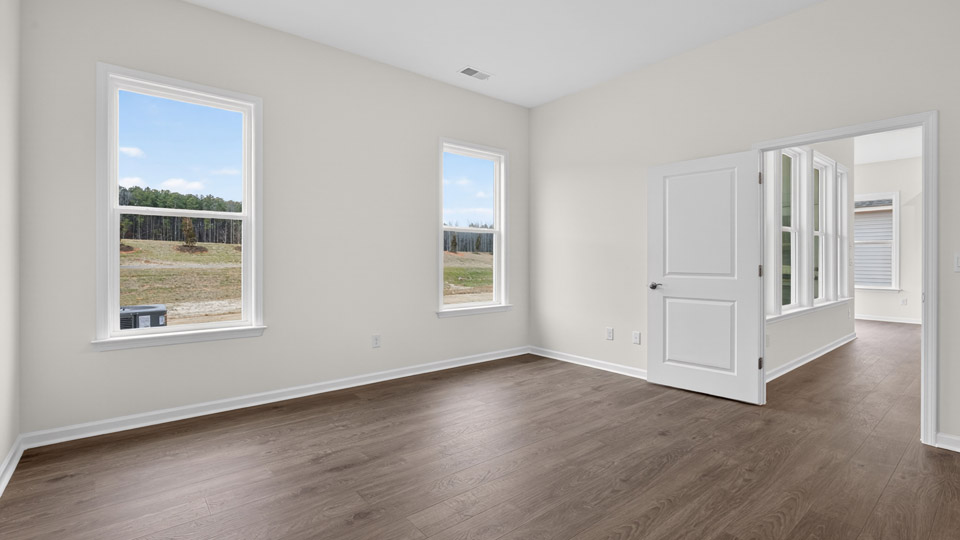 Primary bedroom with hardwood floors and windows with access to the primary bathroom