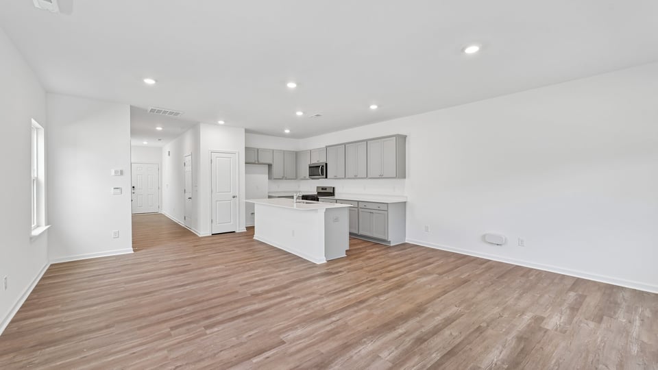 open concept living and dining areas overlooked by kitchen