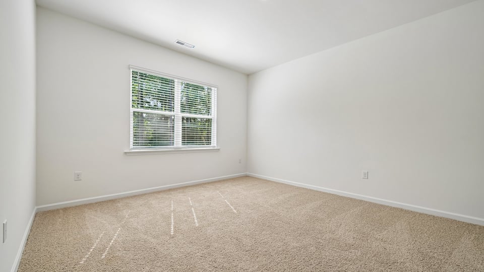 primary bedroom with two windows and carpeting, attached bath
