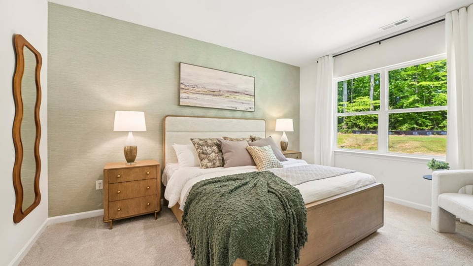 primary bedroom with two windows and carpeting, attached bath