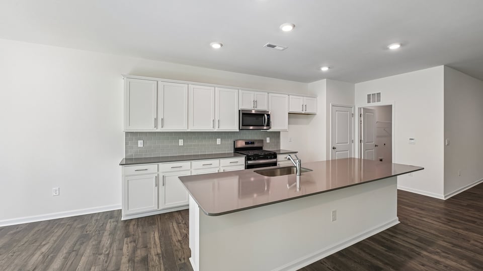 kitchen with quartz counters, kitchen island, pantry, stainless steel appliances