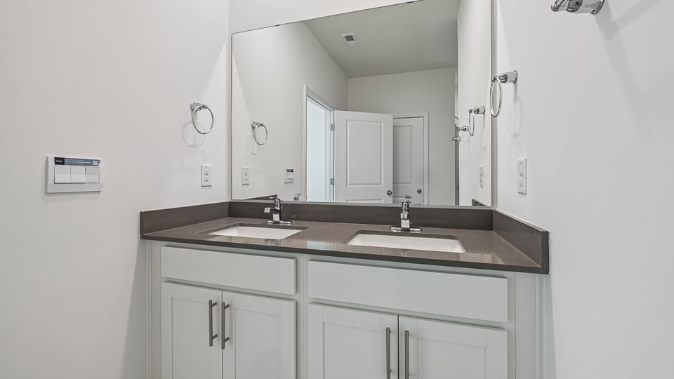 primary bathroom with walk in shower and dual vanity sinks