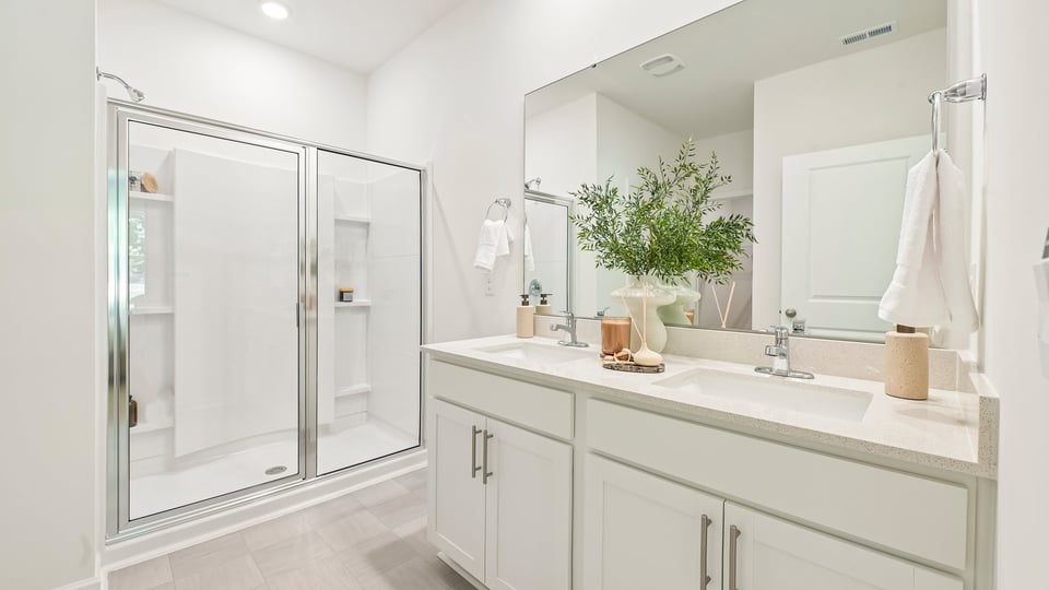 primary bathroom with walk in shower and dual vanity sinks