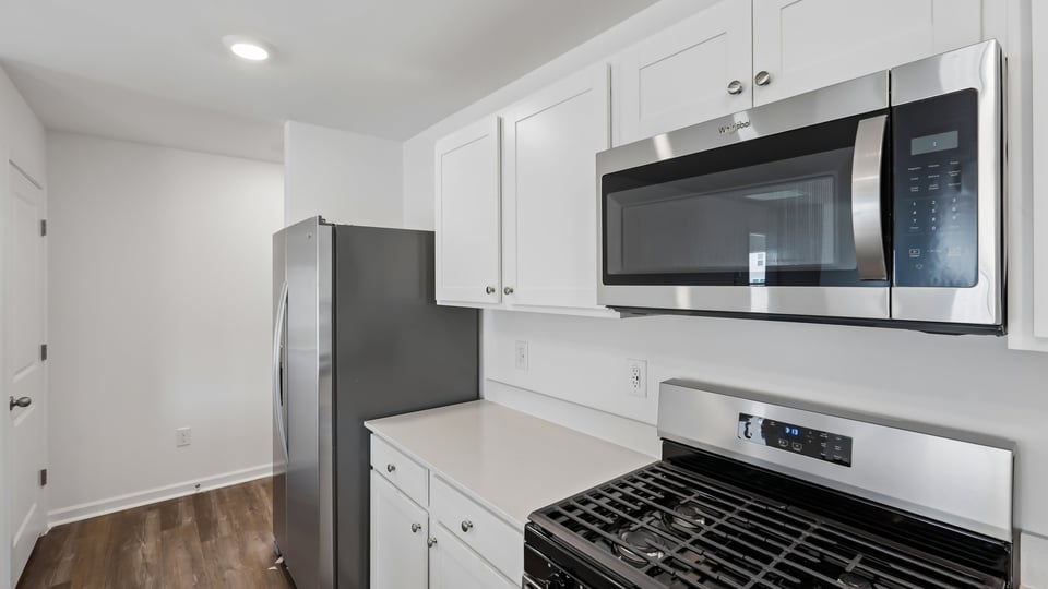 kitchen with quartz counters, kitchen island, pantry, stainless steel appliances