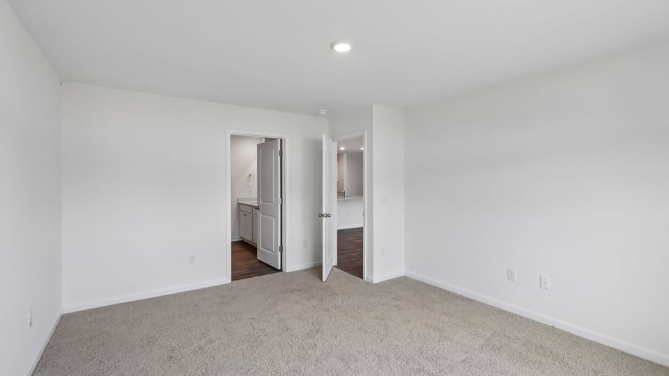 primary bedroom with two windows and carpeting, attached bath