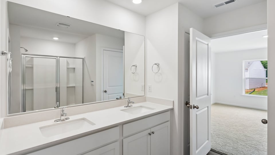 primary bathroom with walk in shower and dual vanity sinks