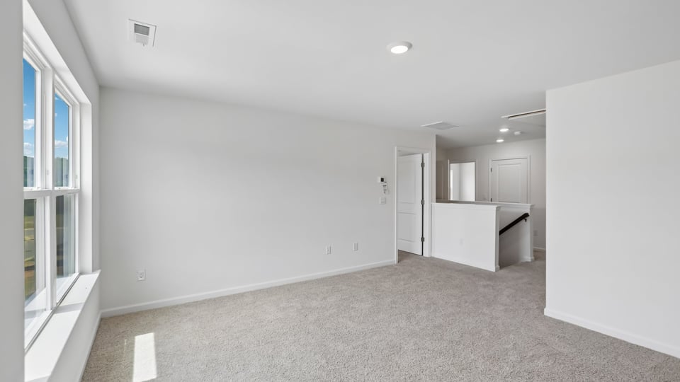 upstairs loft area with large windows and carpeting
