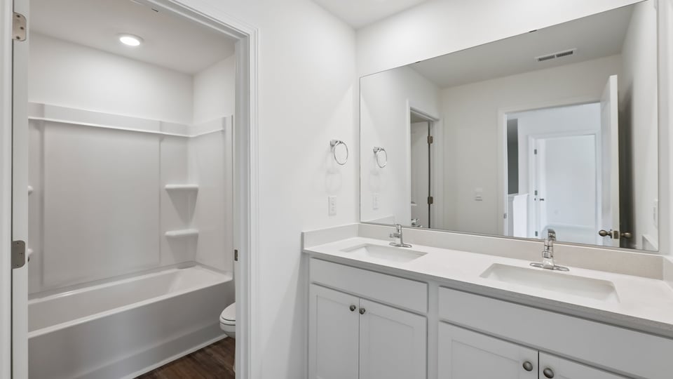 secondary bathroom with shower tub combo and dual vanity sink