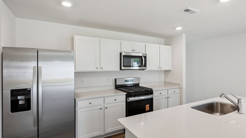 kitchen with quartz counters, kitchen island, pantry, stainless steel appliances