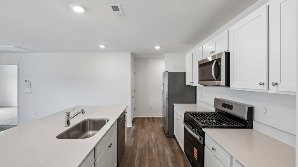 kitchen with quartz counters, kitchen island, pantry, stainless steel appliances