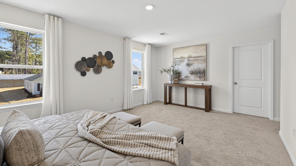 primary bedroom with two windows and carpeting, attached bath