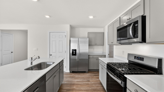 kitchen with quartz counters, kitchen island, pantry, stainless steel appliances