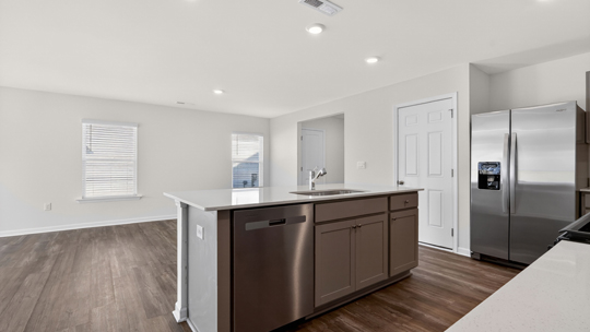 kitchen with quartz counters, kitchen island, pantry, stainless steel appliances