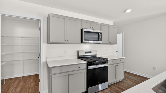 kitchen with quartz counters, kitchen island, pantry, stainless steel appliances