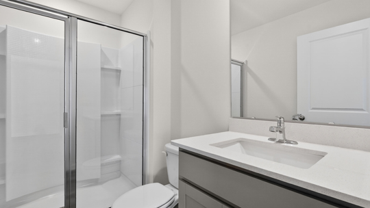 secondary bathroom with walk in shower and single vanity sink