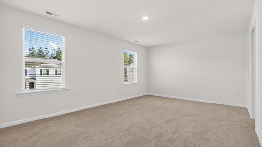 primary bedroom with two windows and carpeting, attached bath