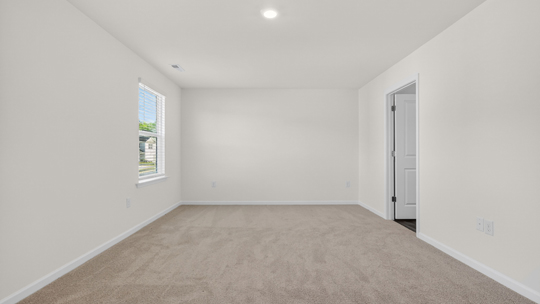 primary bedroom with two windows and carpeting, attached bath