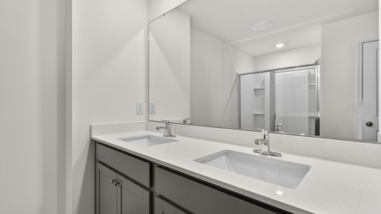 primary bathroom with walk in shower and dual vanity sinks