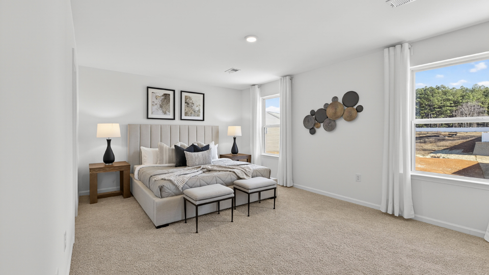 primary bedroom with two windows and carpeting, attached bath